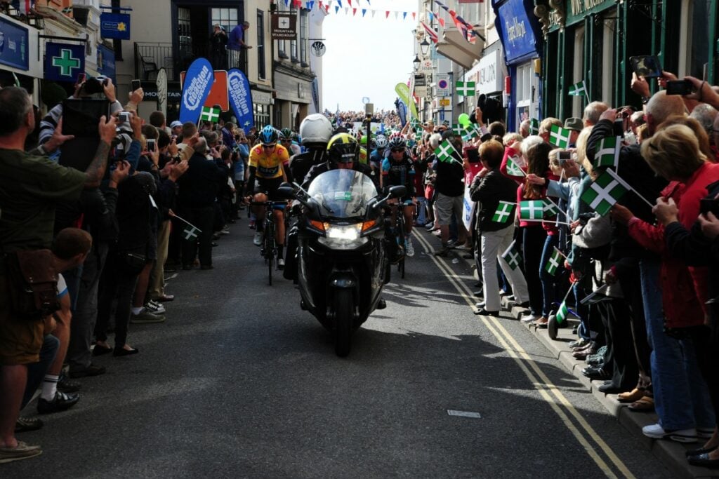 The cyclists making their way through the crowds in a busy Devon street